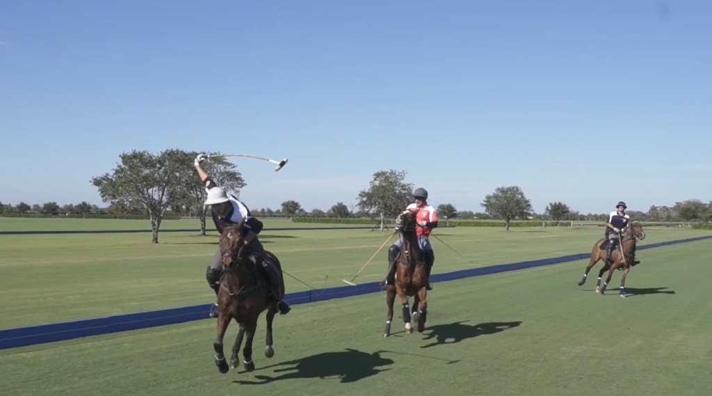 three people on the horses during polo game, trees on the field
