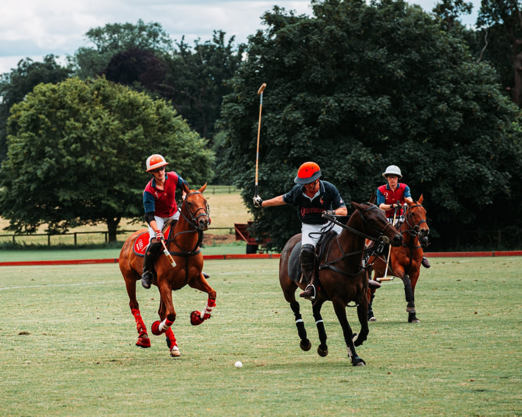 Two men on horseback hold clubs in their hands and try to hit the ball