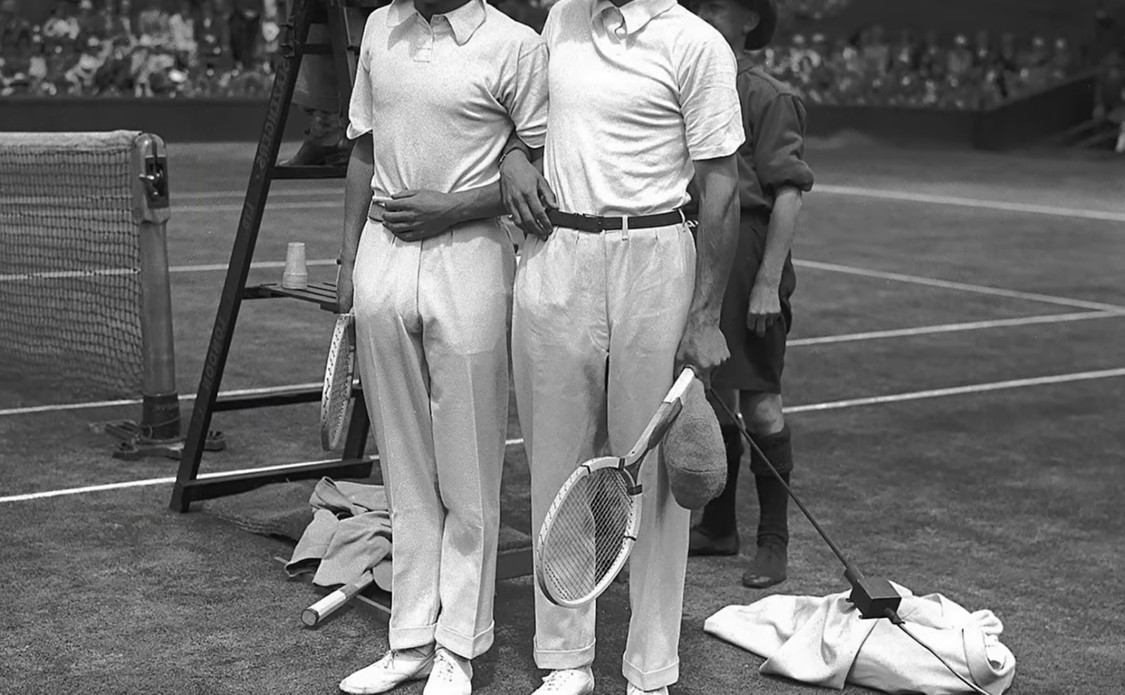 two tennis players in white clothing and polo shirts holding rackets on a field